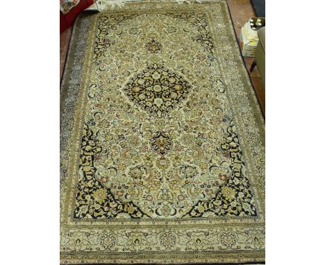 An Iranian Qum silk rug, 2nd half of 20th century, beige ground with central medallion and spandrels on black ground, worked 