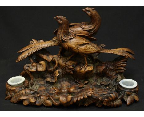 A 19th century German Blackforest carved inkwell, formed as two cock pheasants standing before a pen tray with ink wells eith