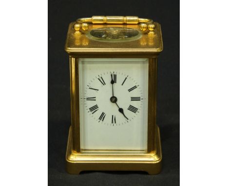 A 20th century brass carriage clock timepiece, the white enamel dial with black Roman numerals, with swing handle and plain c