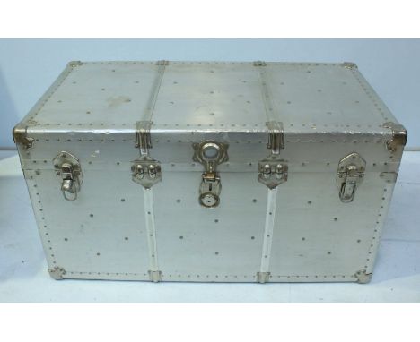 A large stainless steel travelling trunk of riveted construction with leather carrying handles. 102 cm wide.