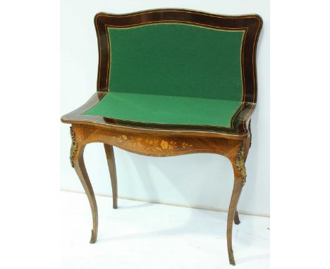 An Edwardian rosewood folding card table, of rectangular form with serpentine front edge, the top and shaped frieze inlaid wi