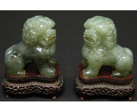 A pair of 20th century carved jade dogs of foe, supported on ornately carved hardwood bases.