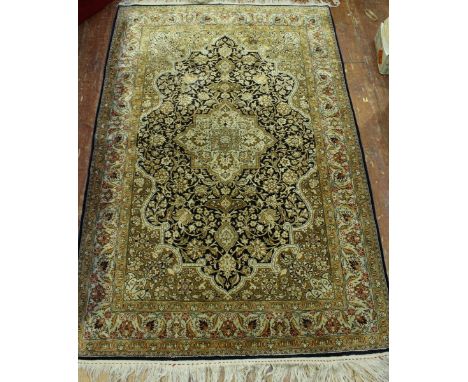 A modern Iranian Qum silk rug, with central medallion and spandrels to a dark blue ground, within Herati borders, worked in k