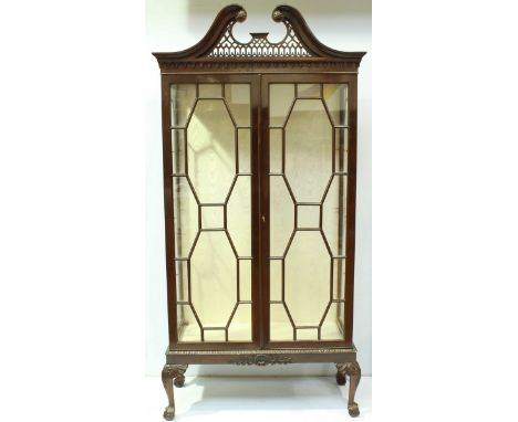 A good quality reproduction mahogany two-door display cabinet in the Chippendale "style," with pierced-trellis swan-neck pedi