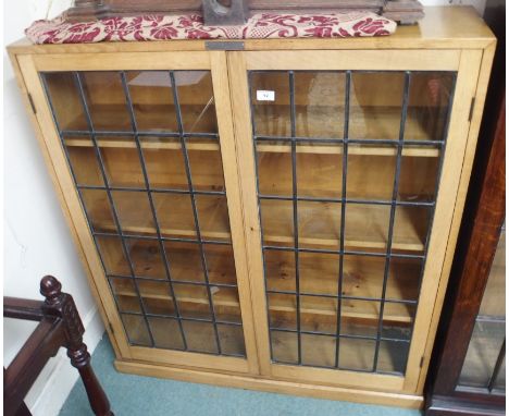 A light oak bookcase with leaded glass doors, 118cm high x 108cm wide Condition Report: Available upon request