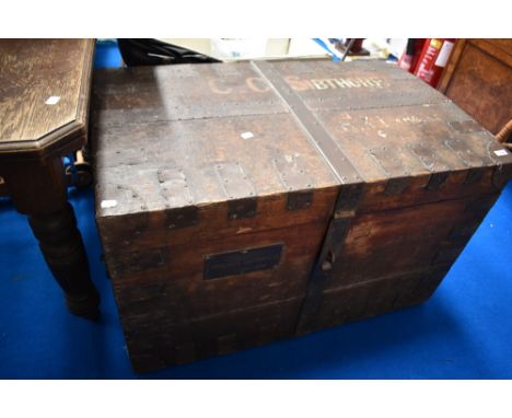 An antique shipping trunk with various names and brass label to side