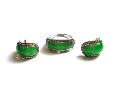 An 18ct white gold, jade and diamond set ring, mounted with the curved saddle shaped jade at the centre and with a row of thr
