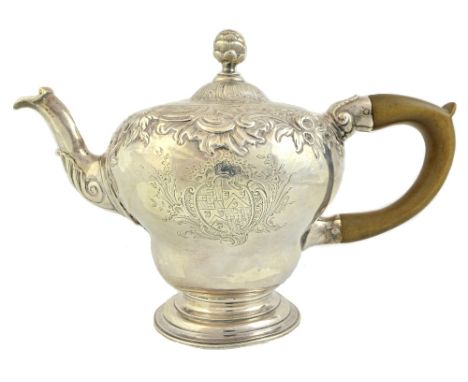 A George II silver teapot, of inverted pear shaped form, decorated with rococo scrolls and flowers, the unmarked hinged lid w