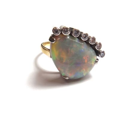 A gold, opal and diamond set ring, mounted with a curved three sided opal and with a row of seven collet set circular cut dia