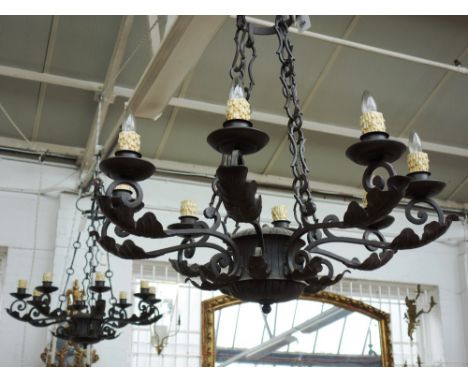 A pair of English wrought iron eight light chandeliers, late 20th century, each cage frame applied with large leaf foliate su
