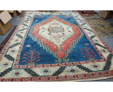 A Turkish carpet, the indigo field with a large ivory and madder medallion, plants to each corner, a wide ivory leaf and flow