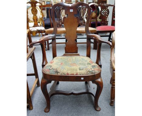 An early 18th century oak and walnut open armchair, with vase splat and cabriole supports, on pad feet and shaped stretcher.