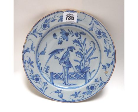 An English delftware blue and white plate, mid 18th century, centrally decorated with a figure holding an exotic bird, within