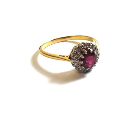 An 18ct gold, ruby and diamond set circular cluster ring, claw set with the circular cut ruby at the centre, within a surroun