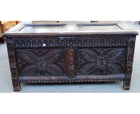 A 17th century oak coffer, the double panel top over carved front, on stile feet, 114cm wide.