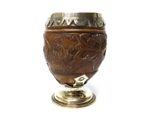 A silver mounted carved coconut goblet, decorated with foliate scrolls and on a circular foot, height 10cm, apparently unmark
