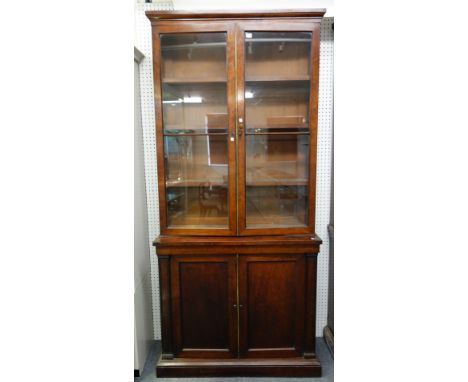 A pair of 19th century plum pudding mahogany bookcase cabinets, each with a pair of glazed doors over pair of panel cupboards