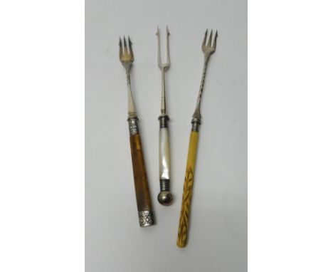 Four plated pickle forks, the carved ivory handles terminating at hooves, a plated pickle fork with a banded agate handle and