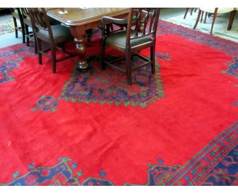 A Turkish carpet, the plain red field with a bold indigo red medallion, matching spandrels, an indigo trailing vine border, 4