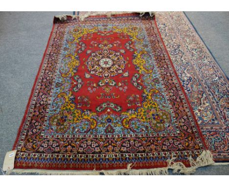 An Indian rug, the madder field with a black medallion an orange and light blue surround; a black floral border 195cm x 125cm