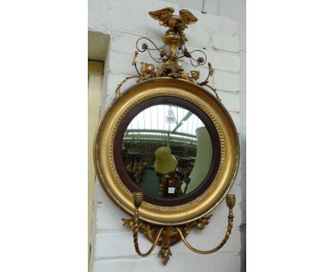 An early 19th century gilt framed convex wall mirror, with eagle surmount and candelabra lower surmount, 46cm wide x 80cm hig