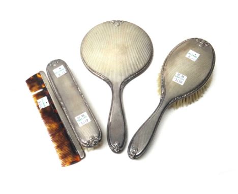 A lady's silver mounted four piece dressing set, comprising; a hand mirror, a hairbrush and a clothes brush, these three Birm