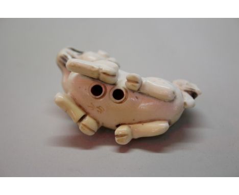 A Japanese carved ivory netsuke of a recumbent lion dog, signed, 5cm long.