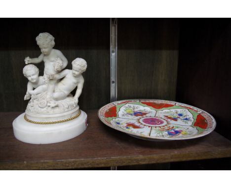 A Parian ware figure group of three putti, on a white marble base, 18cm high; together with a Chamberlain's Worcester plate, 