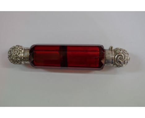 A ruby cut glass double ended scent bottle, having embossed metal caps. 13cm. Condition Report: Stopper missing