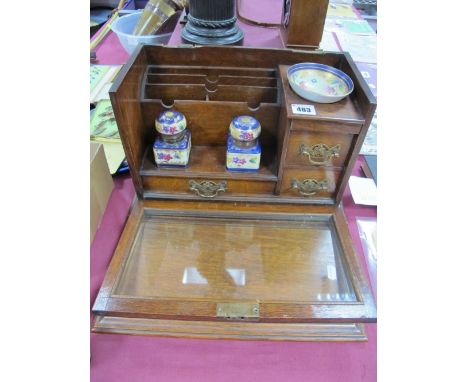 An Early XX Century Oak Stationery Box, with lift up top, glazed drop door, sectional compartments, ceramic inkwells and dish