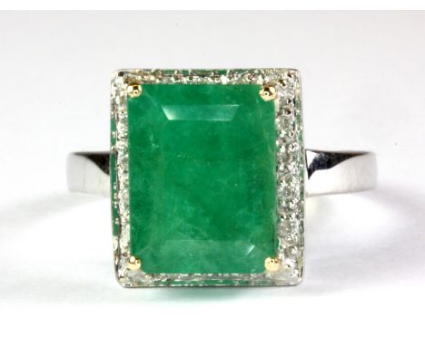 A 9ct white gold ring set with an emerald cut emerald surrounded by diamonds, (emerald approx. 5.3ct) (O).