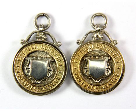 Two silver football medals with yellow gold inserts.