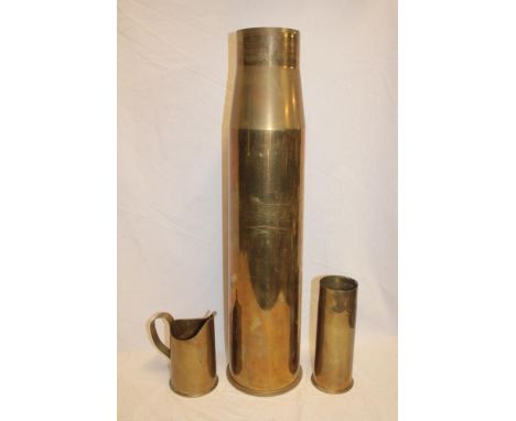 A large brass shell case 27½" high, First War trench-art shell case jug dated 1915 and one other first war brass shell case (
