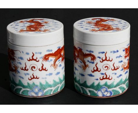 A pair of Chinese jars and covers of cylindrical form decorated dragons chasing a flaming pearl, red seal mark to the undersi