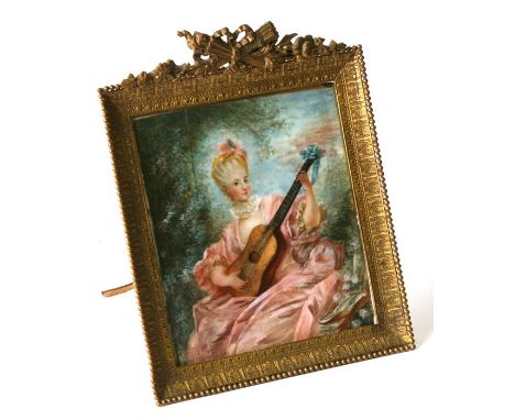 A late 19th century portrait miniature depicting a lady playing a lute, mounted in an ornate metal easel frame, 10 by 11.5cms