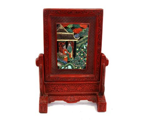 A Chinese cinnabar lacquer table screen with inset rectangular porcelain panel depicting figures, overall 37cms (14.5ins) hig