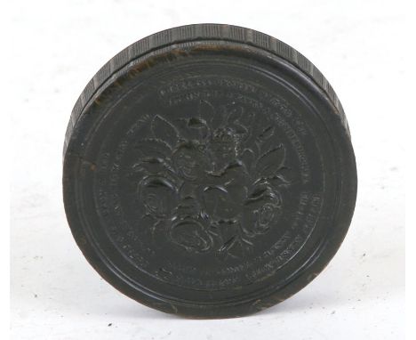 An early 19th century pressed horn circular snuff box by Wilson, the cover decorated in relief with a cherub amongst flowerin