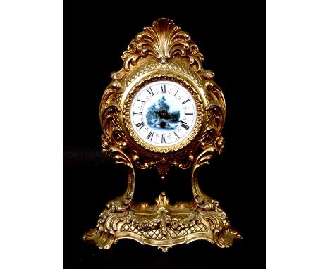 An early 20th century gilt metal Continental mantel clock in the Rococo style, the enamel dial with countryside image, 36 cms