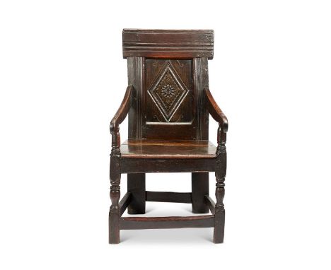 A Charles I oak armchair, North Country
With a lozenge carved panel below a deep moulded top-rail, the downswept arms raised 
