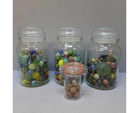 Four jars of vintage marbles including clay 