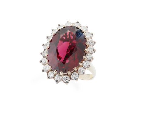 A garnet and diamond cluster ring Claw-set with an oval-cut garnet in a border of round brilliant-cut diamonds, stamped 18ctD