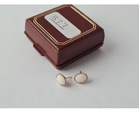 A pair of white opal stud earrings, rope edged in 9ct 