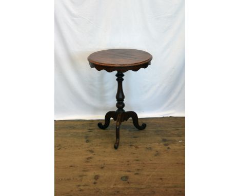 A mahogany circular top occasional table with wavy frieze, on vase shaped stem, tripod legs and scrolled toes.  20ins diamete