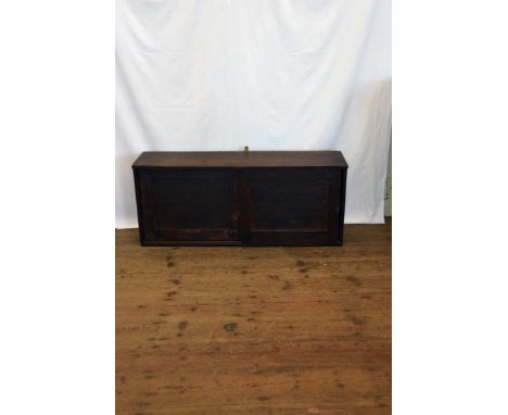 An oak hanging cupboard with two sliding panelled doors opening to reveal an interior shelf.  41¼ins wide.  Est £10-20