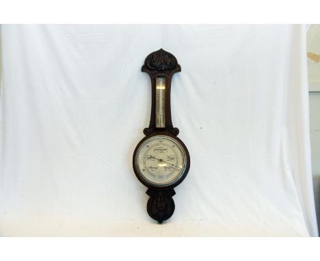 An oak cased barometer/thermometer, the silvered 8ins dial with retailers name John Barker & Co Ltd. Kensington.  33ins.  Est