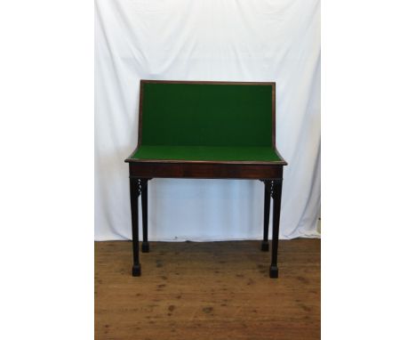 A George III mahogany card table, the rectangular top opening to reveal a green baize lined interior, on reeded tapering legs