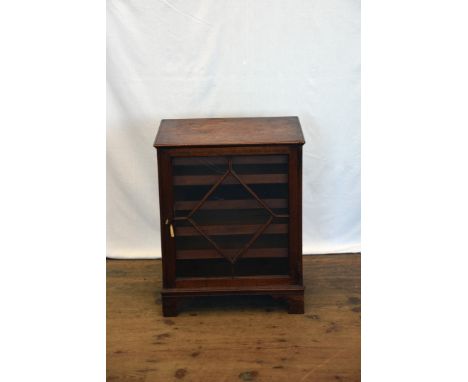 A small early 19th century mahogany cupboard with astragal glazed door opening to reveal four interior sliding trays, on brac