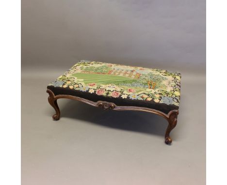 A WALNUT NEEDLEWORK FOOTSTOOL. of large proportions, embroidered with a study of Sheriff Hutton Hall, Yorkshire, within a flo