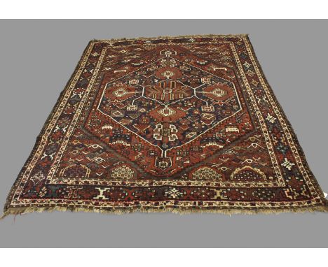 A KHAMSEH RUG, CIRCA 1930. the terracotta field of tribal motifs centred by an indigo medallion framed by spandrels and borde