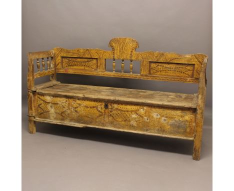 AN EASTERN SETTLE. possibly Indonesian, with a carved and shaped top and sides with turned spindles, the lifting seat enclosi